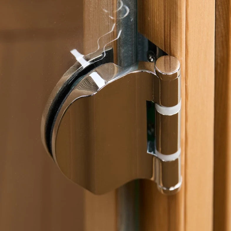 Close-up of a metal door stopper and latch mechanism attached to a wooden door frame on a Holl's Moon 1 wooden sauna cabin