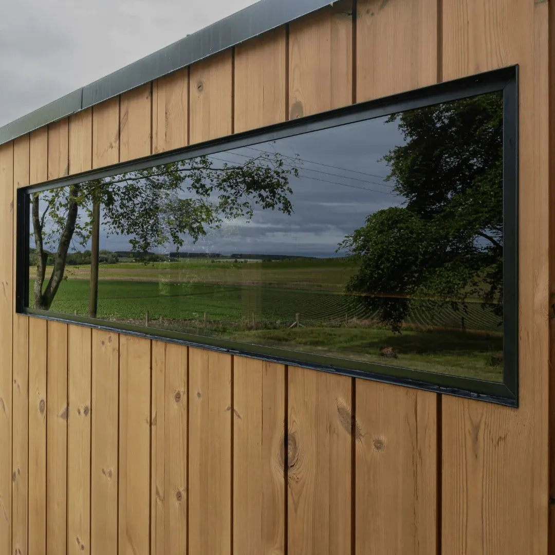 AIRA exterior detail: black aluminium framed window in thermo pine cladding