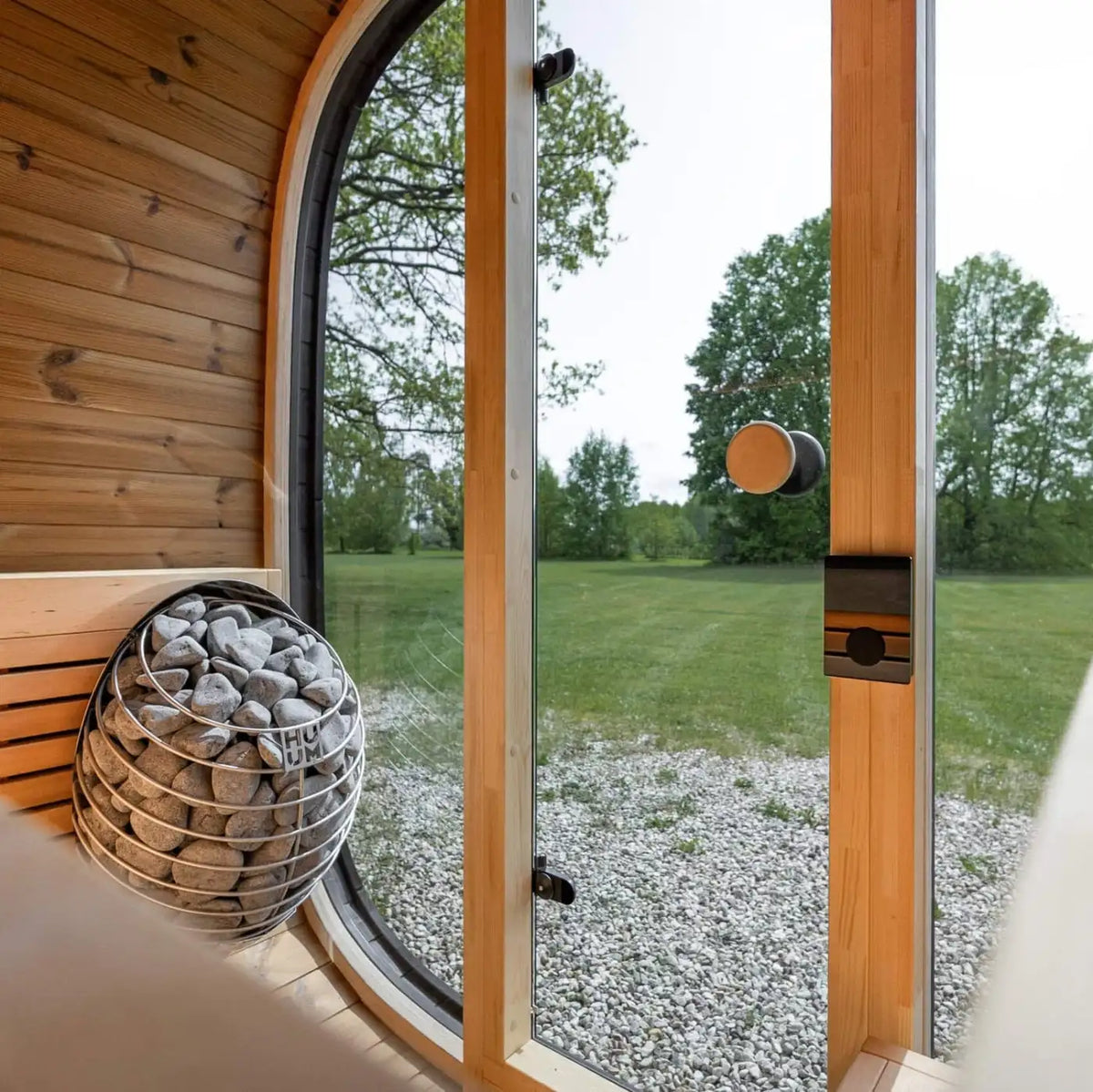Holl's Onyxia Cube outdoor sauna heater with stones seen through the glazed corner