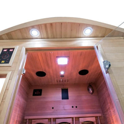 France Sauna Apollon 3C: Corner Infrared Sauna with an open door showing the interior, warm ambient lighting, ceiling lights, speakers, and a control panel on the left side.