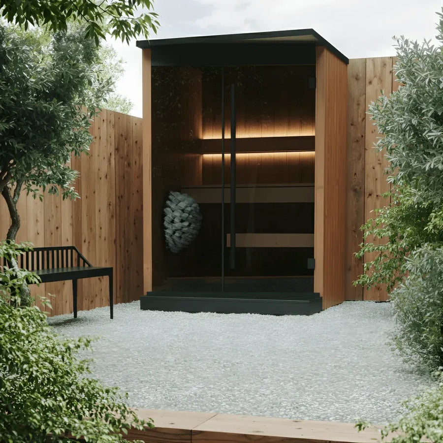EMBA two person outdoor sauna in natural thermo pine with a glass front, in a gravel courtyard