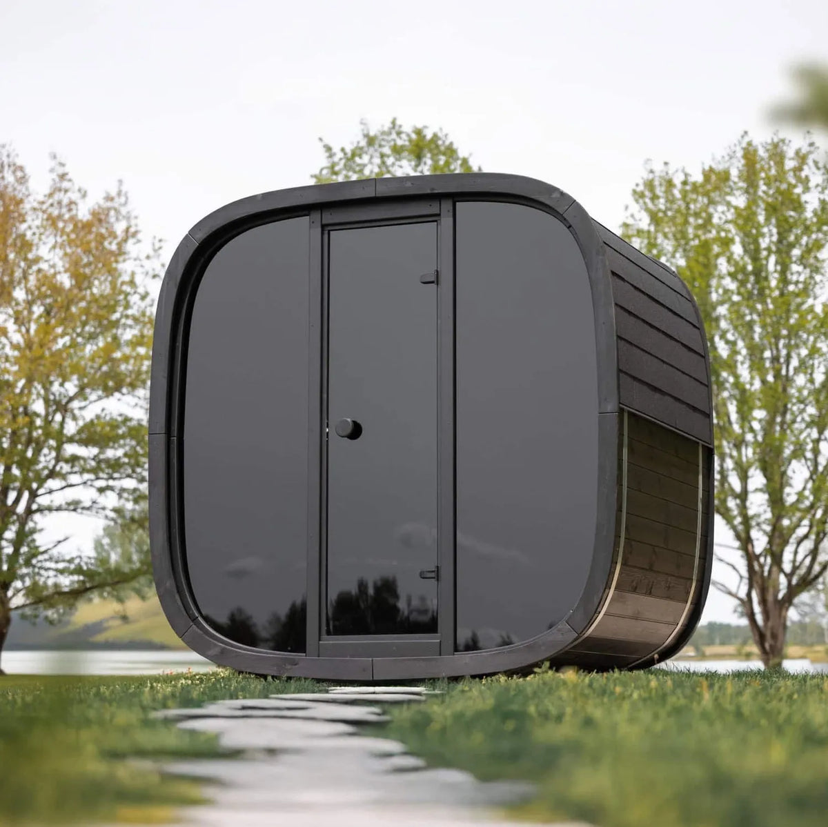 Holl's Onyxia Cube glazed front outdoor sauna on a lawn with trees behind