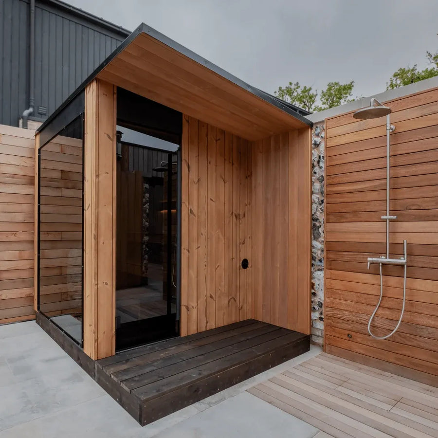 URSA outdoor sauna with its side overhang, installed beside an outdoor shower