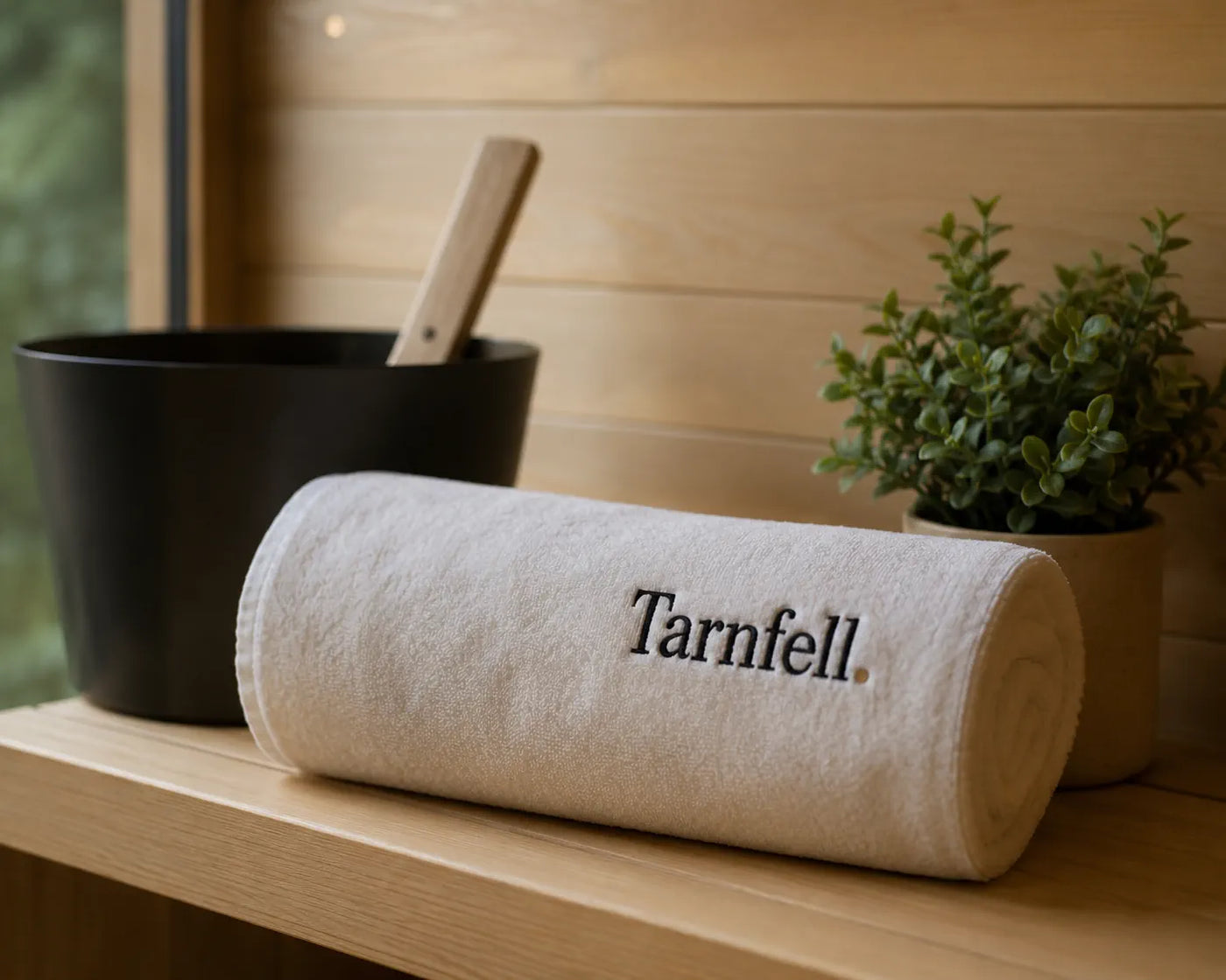 Tarnfell white Microcotton bath sheet rolled on a sauna bench beside a bucket and ladle