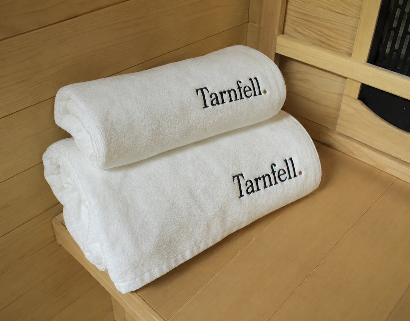 Tarnfell white Microcotton bath sheets stacked, showing the cotton pile and embroidered wordmark